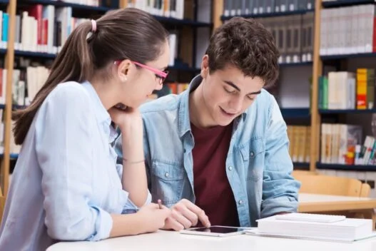 Kvinde der giver en mandlig studerende lektiehjælp i gymnasiet